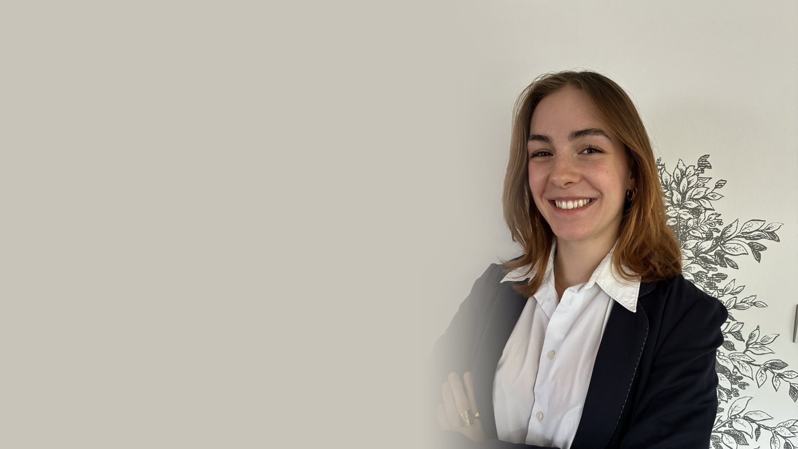 Portrait d’Elsa Sabin, souriante, en veste sombre et chemise blanche, bras croisés