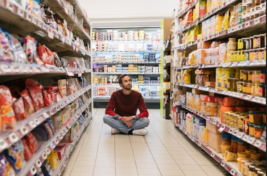 Jean Moreau, fondateur de Phenix, assis dans une allée de supermarché
