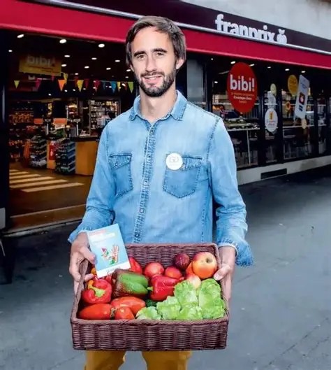 Jean Moreau devant un magasin Franprix avec un panier de fruits et légumes