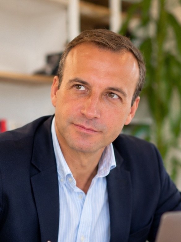 Portrait de Jérôme Mendoza-Trussart en veste bleu marine, à son bureau