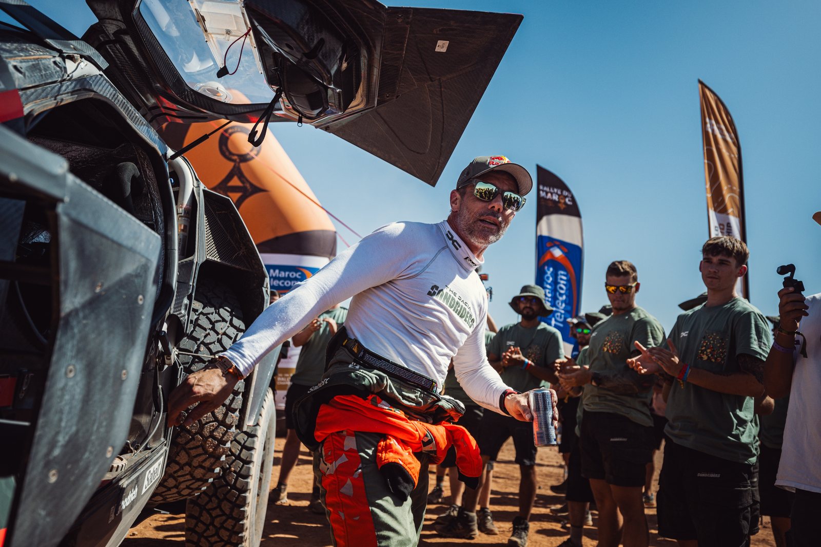 Sébastien Loeb climbing out of his car at the Rallye du Maroc, applauded by the team