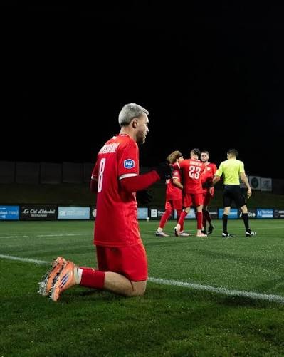 Tom Frayssinous à genoux sur la pelouse sous le maillot rouge de Beauvais