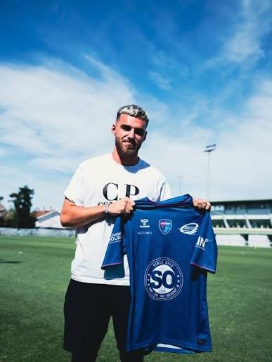 Tom Frayssinous tenant le maillot bleu du FBBP 01 sur un terrain de football